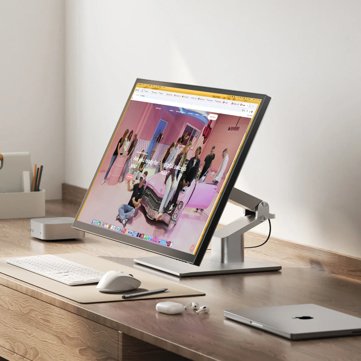 Modern home office setup with touchscreen monitor, macbook, speakers, microphone, and headphones on a desk.